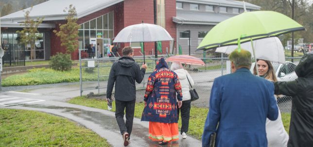 Guest arrive at UFV's Agricultural Centre of Excellence for the Celebration of Community. They're holding umbrellas but cheerful in the rain.